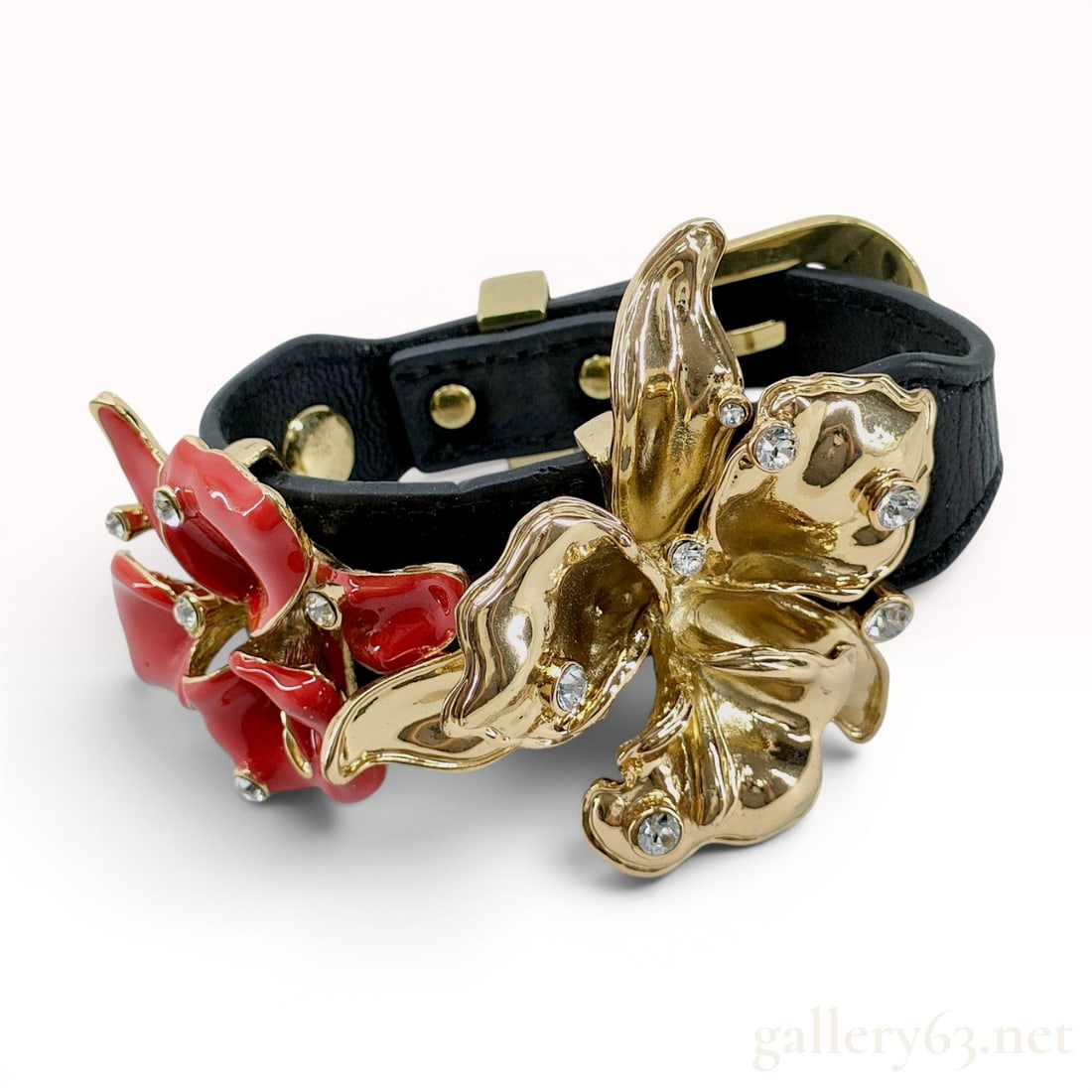 Versace for H&M Black Leather Floral Statement Bracelet with Enamel and Crystals: A Versace for H&M statement bracelet from the 2011 collaboration collection. The piece is constructed with a black textured leather strap featuring two prominent three-dimensional floral elements. One