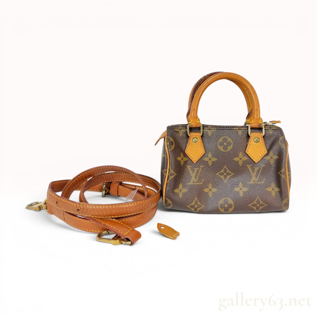 Louis Vuitton Monogram Nano Speedy Mini HL Handbag with Shoulder Strap: A Louis Vuitton Nano Speedy handbag, also known as the Mini HL, crafted from signature monogram coated canvas. The bag features natural vachetta leather rolled top handles and trim. It includes a long