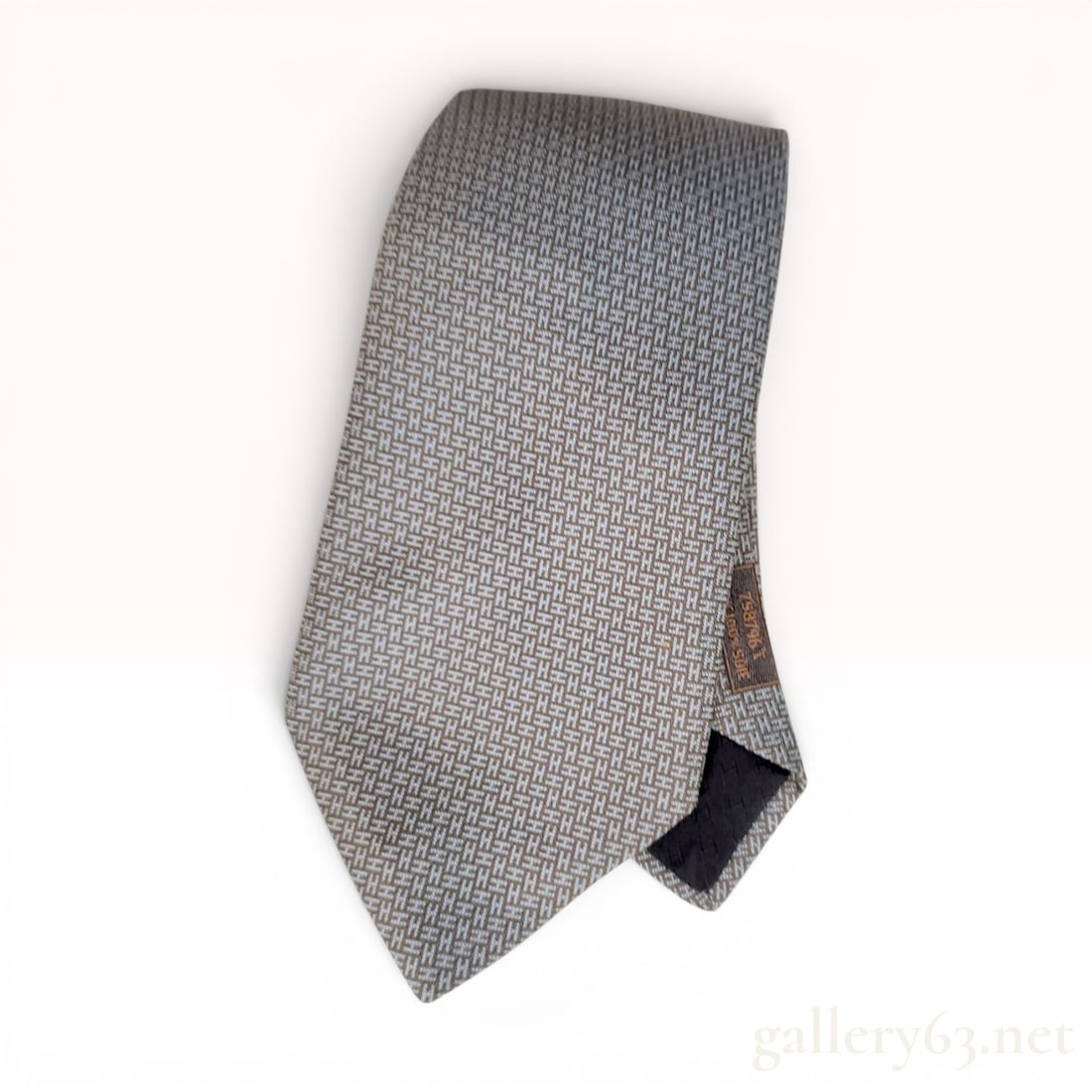Hermes Paris Woven Silk Necktie Model 758796 T: An authentic Hermes Paris silk necktie, model number 758796 T. The tie is constructed from 100 percent silk featuring a micro-woven geometric pattern of repeating H motifs in light blue and chocolate 