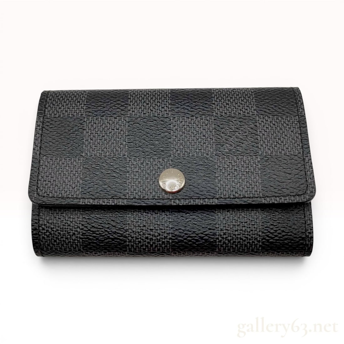 Louis Vuitton Damier Graphite Multicles 6 Key Holder: A Louis Vuitton Multicles 6 key holder featuring a Damier Graphite coated canvas exterior in a black and gray checkered pattern. The compact trifold design is secured by a single silver-tone snap-butt