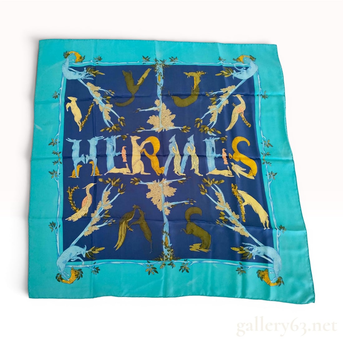 Hermes Alphabet III Silk Scarf: This Hermes silk scarf features the Alphabet III pattern, characterized by the brand name HERMES spelled out in the center using various animal figures. The design is set against a navy blue field and
