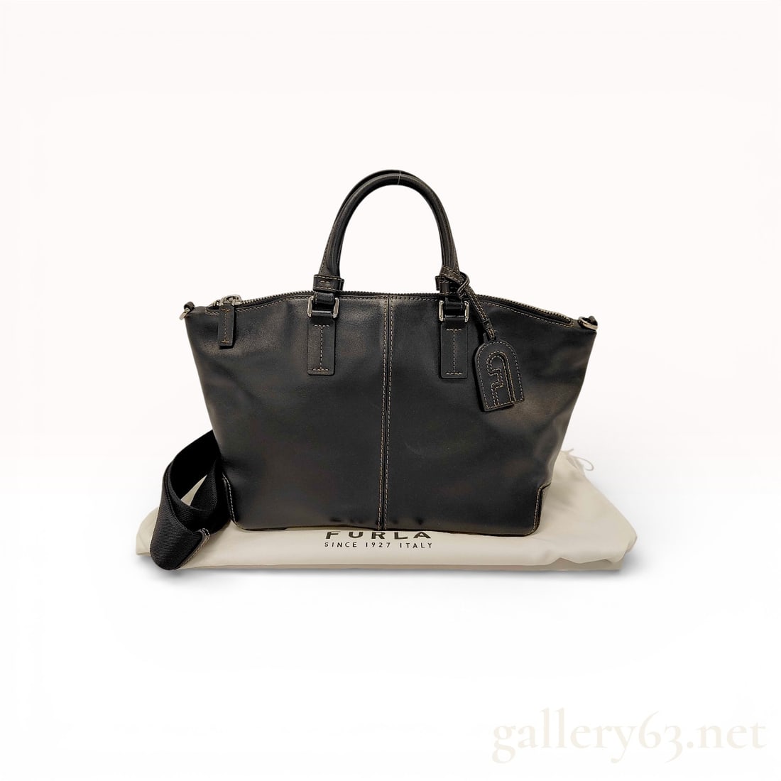 Furla Sirio Leather Tote Bag with Dust Bag: Authentic Furla Sirio tote bag in balck smooth leather, featuring a structured trapezoidal silhouette with contrast topstitching and center seam detail. The design includes dual rolled top handles wit