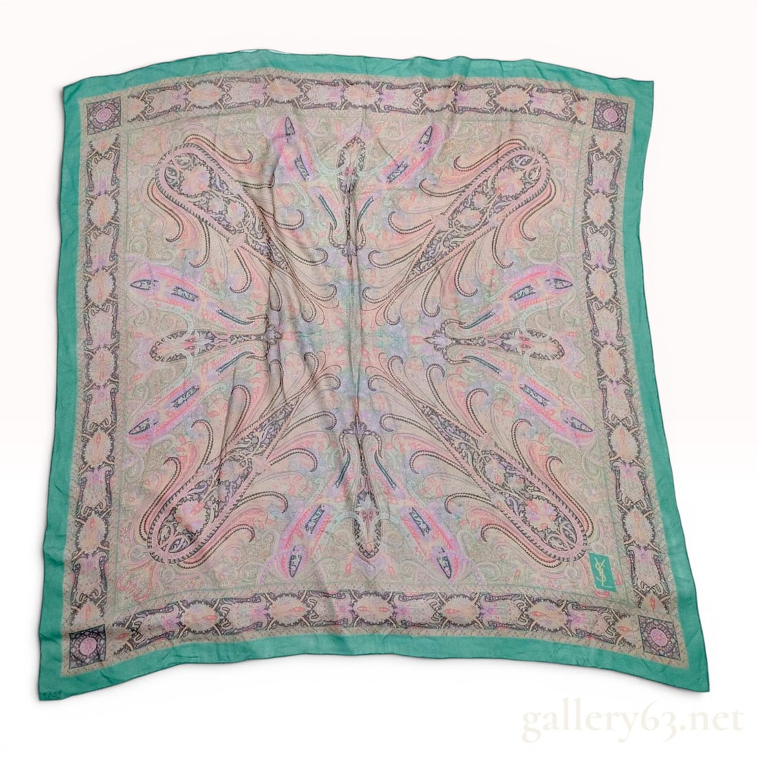 Yves Saint Laurent Large Paisley Print Silk Foulard: Large square silk foulard by Yves Saint Laurent. The garment features an intricate multi-color paisley pattern in shades of pink, lavender, tan, and light green. The design is framed by a wide emerald