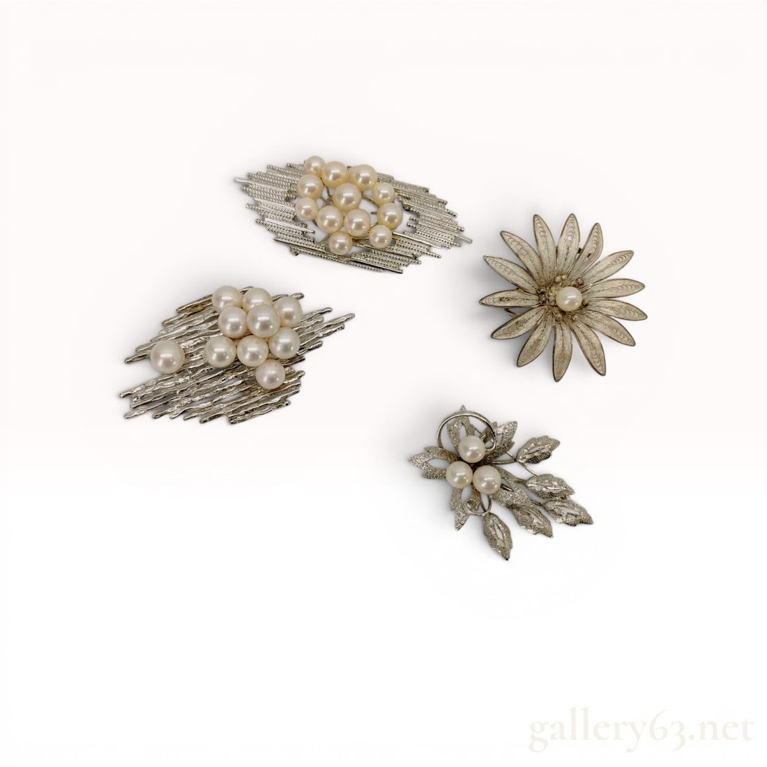 A Group of Mid-Century Sterling Silver and Cultured Pearl Pendants/Brooches: Collection of vintage sterling silver and cultured pearl jewelry featuring two modernist brutalist-style cluster pins, a filigree floral brooch, and a botanical leaf spray pin. The pieces showcase tex