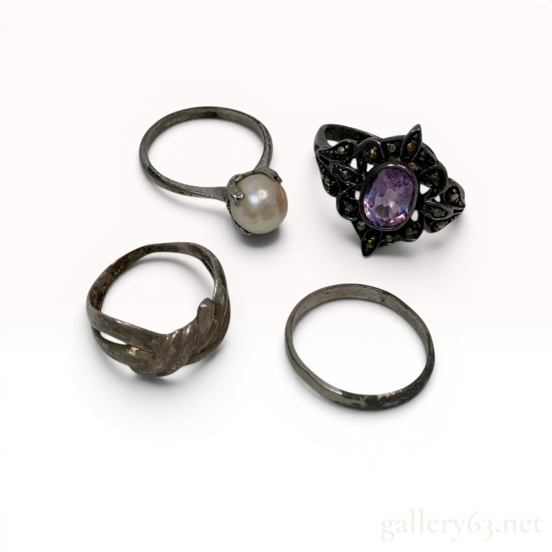 Collection of Four Vintage Sterling Silver Rings: An assortment of four sterling silver rings in various designs, including a solitaire pearl ring and a marcasite cocktail ring. The collection features a white pearl measuring approximately 7.5mm in a