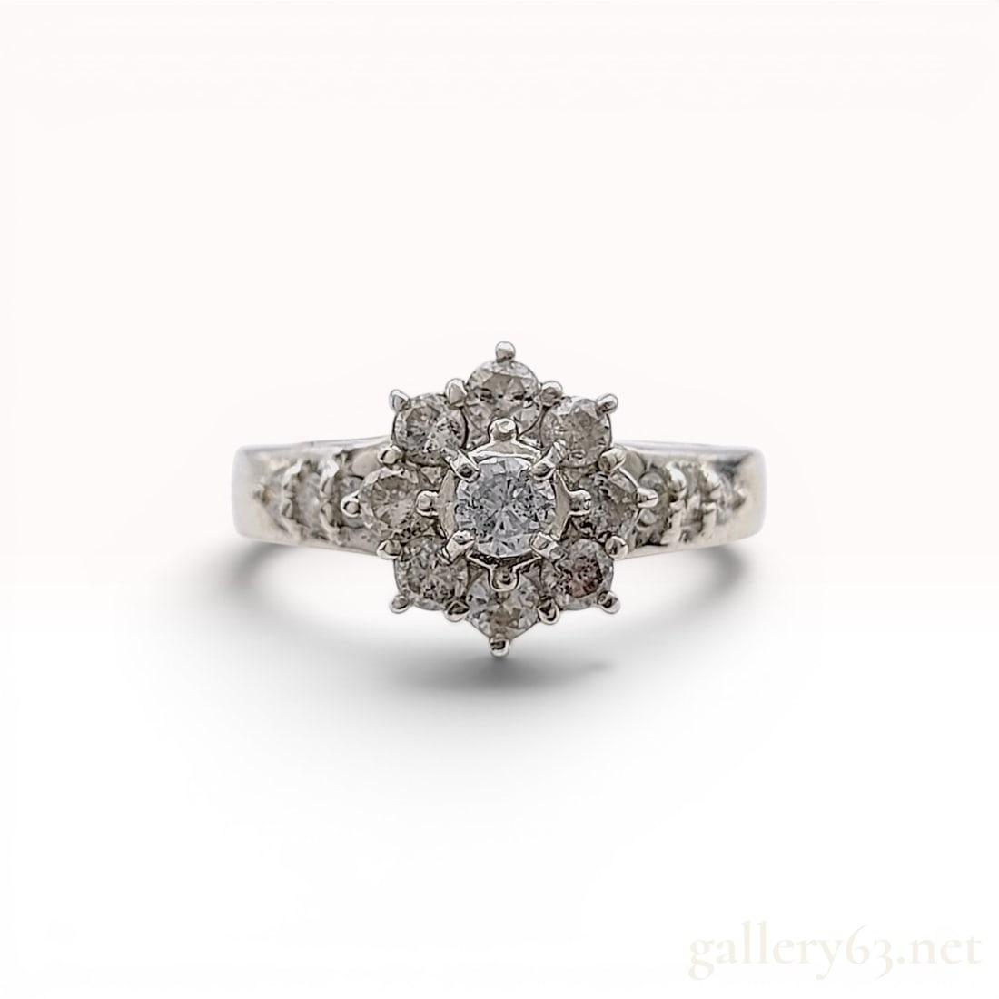 Platinum 900 and Natural Diamond Flower Cluster Ring: Platinum floral cluster ring featuring.50ctw natural near-colorless round brilliant-cut diamonds, late 20th century. The tiered design includes a central raised diamond, a halo, and bead-set shoulder 