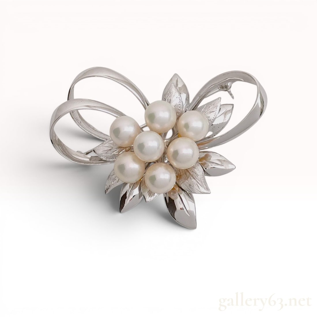 Vintage Japanese Silver and Akoya Cultured Pearl Floral Ribbon Brooch: Mid-20th century Japanese floral spray brooch featuring a cluster of seven round Akoya cultured pearls. The botanical design is composed of textured and polished silver leaves accented by a smooth dou