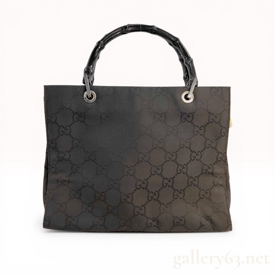 Gucci Black GG Monogram Bamboo Handle Tote Bag: Gucci black GG monogram jacquard tote bag with signature black lacquered bamboo handles. The structured open-top design features silver-tone grommets and a black fabric-lined interior with a single si
