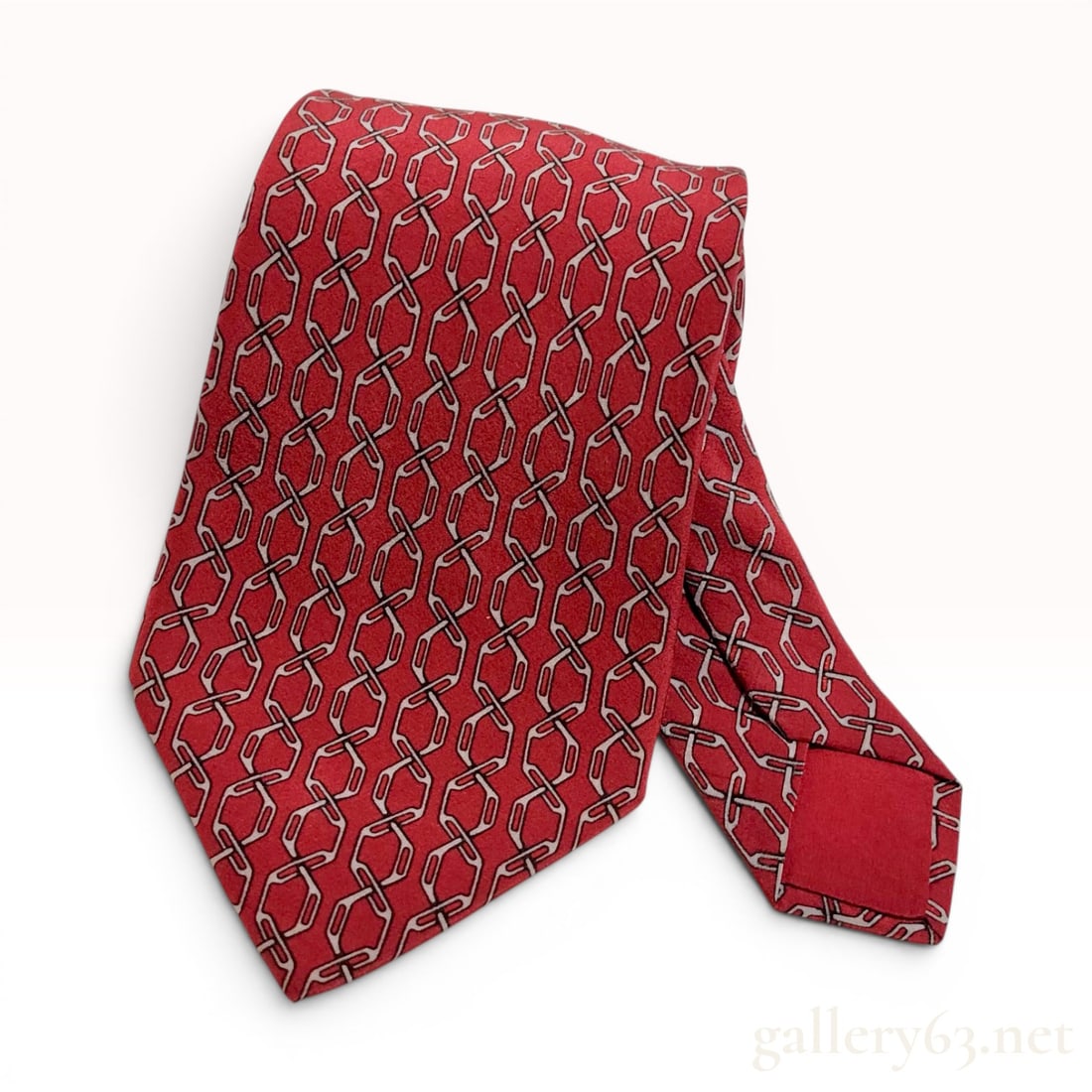 Hermes Paris Silk Necktie Pattern 897 PA Red Geometric Chain Link: This Hermes Paris necktie is crafted from 100% silk and features an interlocking geometric chain link pattern in light gray and black on a red ground. The reverse narrow end displays a printed horse-d