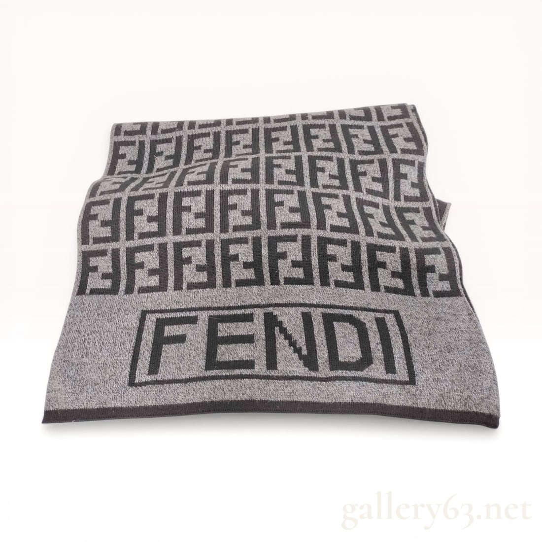 Fendi Zucca Monogram Knit Wool Scarf: Fendi knit wool scarf featuring the signature all-over Zucca double-F monogram pattern in charcoal grey and black. The design includes large block FENDI text at the ends and a sewn-in Fendi Mare Roma 