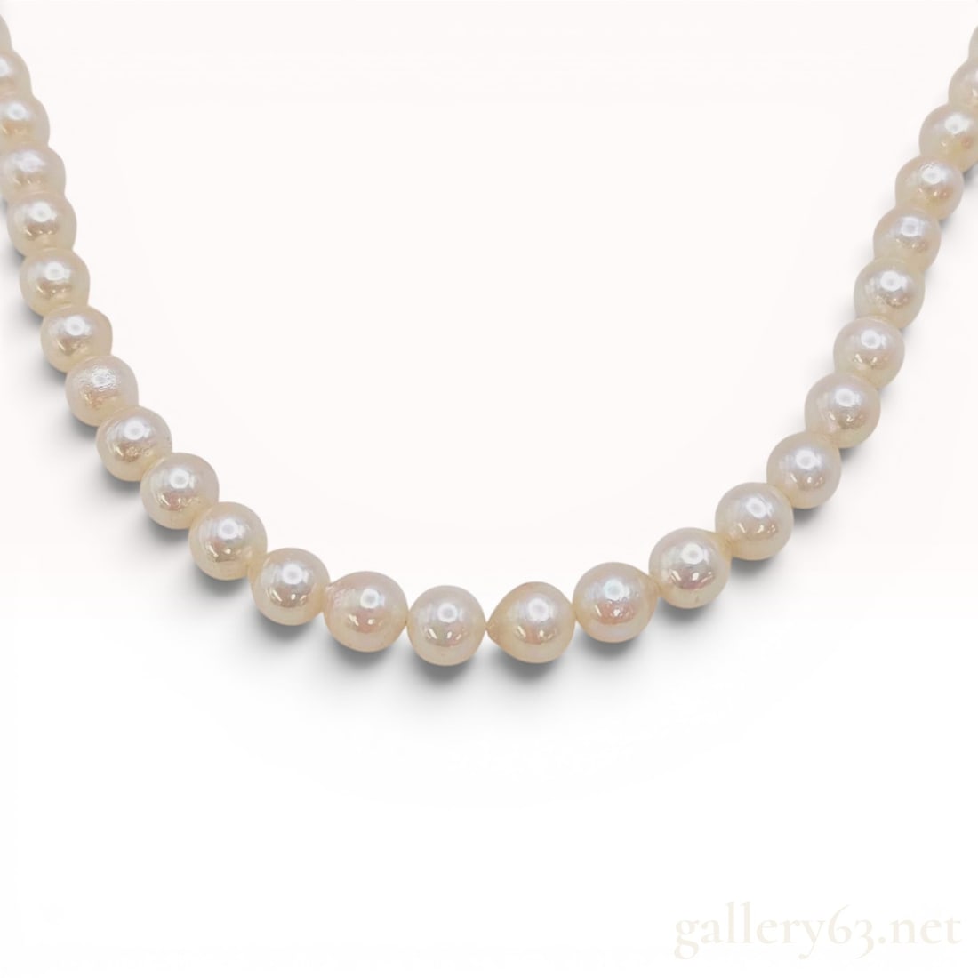Single Strand Cultured Pearl Necklace with Silver Floral Clasp: A single-strand cultured pearl necklace featuring near-round pearls with a creamy white body color and pinkish overtones. The pearls are individually knotted on a white cord for security. The necklace