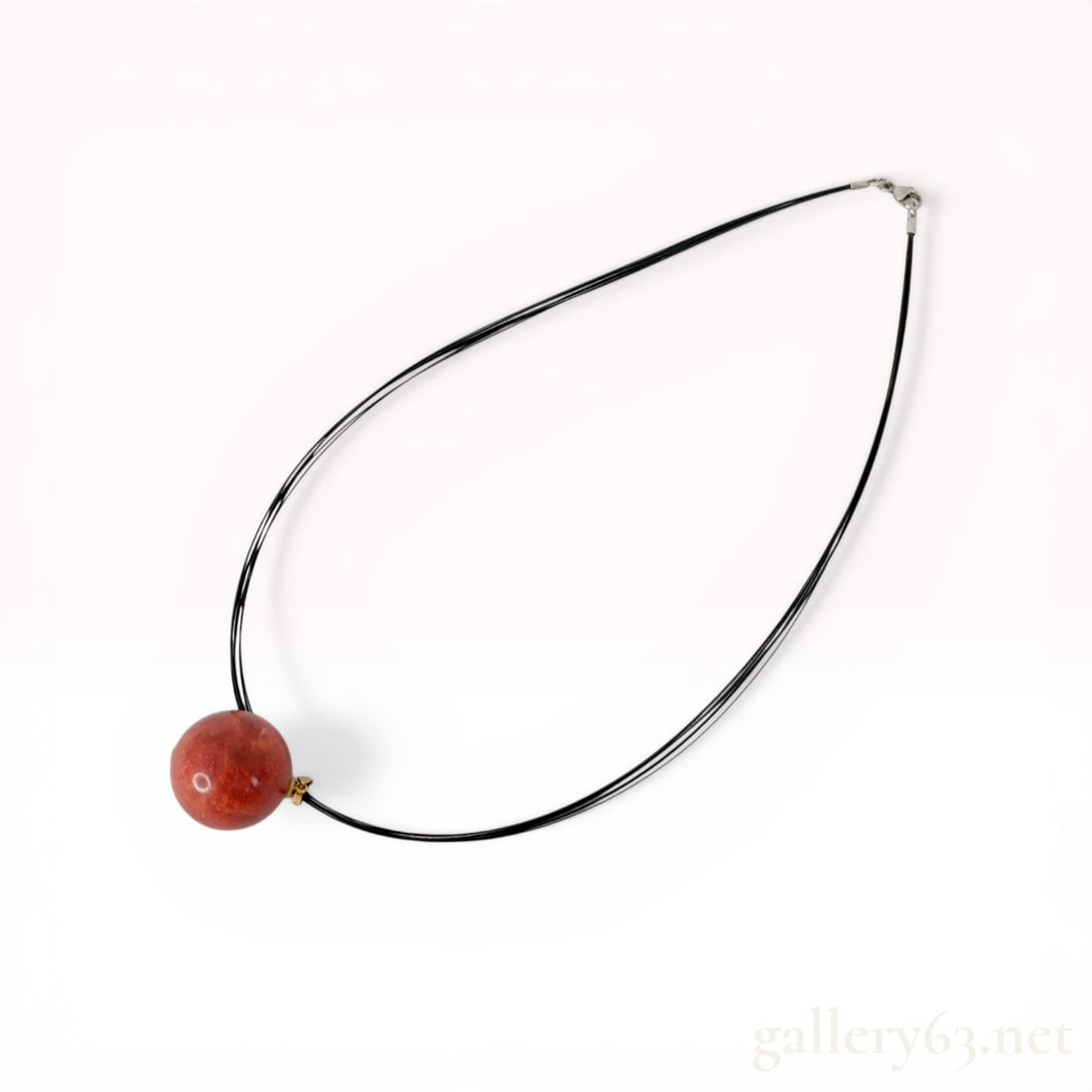 Multi-Strand Pendant Necklace with 18K Gold and Sterling Silver Hardware: Contemporary pendant necklace featuring a large spherical mottled red stone bead, approximately 25mm in diameter, suspended from an 18 karat yellow gold bail. The necklace is composed of five thin bla