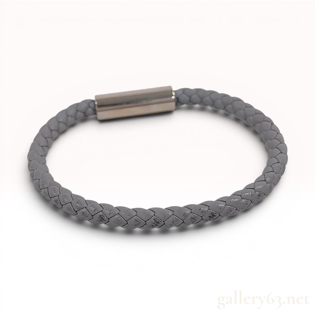 Hermes Gray Braided Leather Bracelet: An Hermes braided leather bracelet featuring a single strand of gray braided leather cord. The bracelet is secured with a silver-tone metal cylindrical barrel clasp that utilizes a push-button release