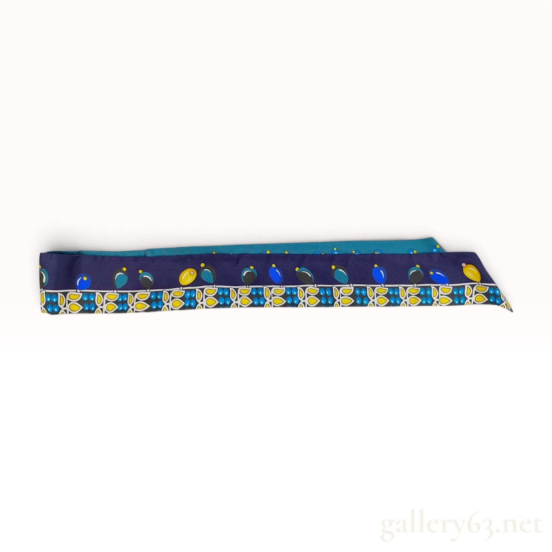 Hermes Silk Twilly Scarf with Stylized Bird and Floral Motif: An authentic Hermes silk Twilly scarf featuring a colorful stylized bird and floral pattern. The design features a dark navy blue background on one side, decorated with a row of oval bird-like shapes 