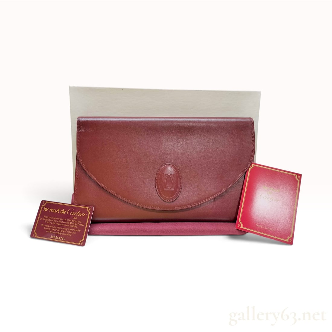 Must de Cartier Burgundy Leather Envelope Clutch Bag: A vintage Must de Cartier envelope-style clutch bag crafted from smooth burgundy calfskin leather. The front flap features an embossed oval medallion with the interlocking C logo. The interior is line