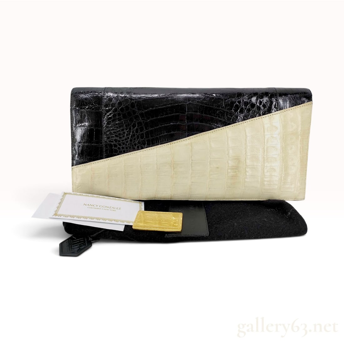 Nancy Gonzalez Two-Tone Caiman Skin Asymmetric Fold-Over Clutch: A Nancy Gonzalez luxury clutch bag featuring a two-tone asymmetric fold-over design. The exterior is constructed from glossy black and cream genuine caiman skin. The bag features hidden magnetic closu