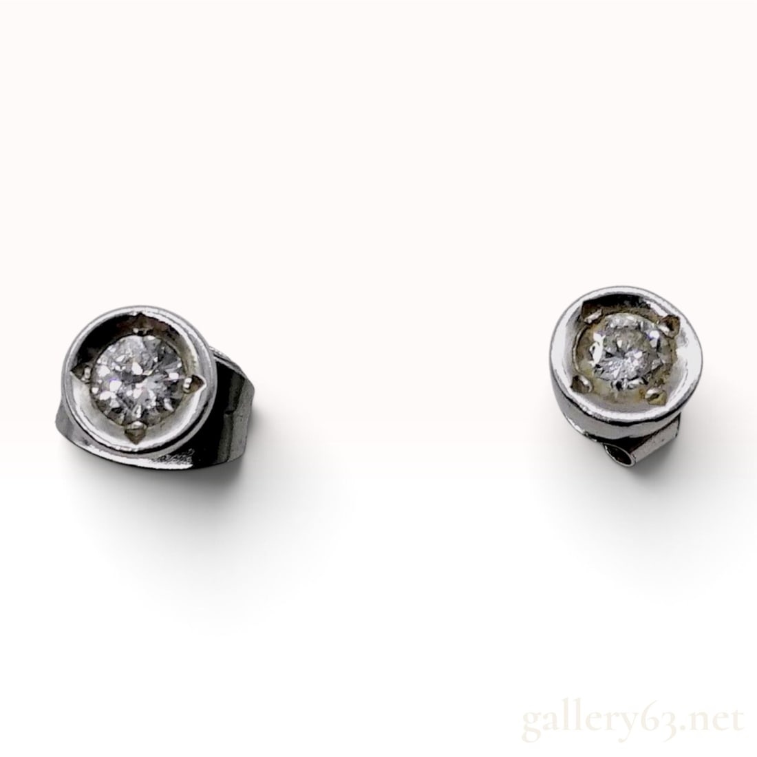 14 Karat White Gold and 0.22ctw Natural Diamond Bezel Stud Earrings: This item is in excellent condition. A matched pair of stud earrings crafted from 14 karat white gold. Each earring features a round brilliant-cut natural diamond secured within a circular bezel setti