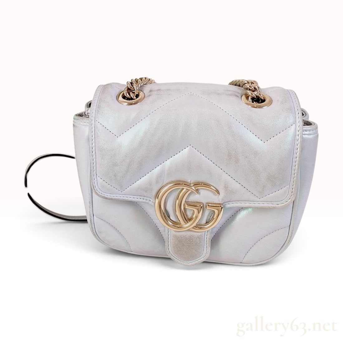 Gucci GG Marmont Mini Iridescent Matelasse Shoulder Bag: This Gucci GG Marmont Mini shoulder bag is crafted from chevron matelasse quilted leather with a pearlescent iridescent finish. The exterior leather exhibits a multi-color sheen that reflects blue, pi