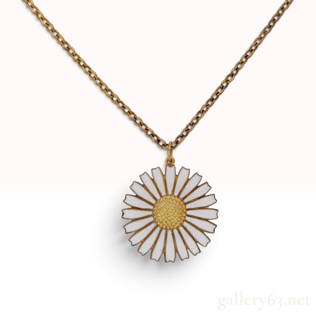 Georg Jensen Gilt Sterling Silver and White Enamel Daisy Pendant Necklace: A Georg Jensen pendant necklace from the Daisy collection. The large, circular pendant is designed in the form of a daisy, featuring radiating white enamel petals surrounding a raised, textured gold-t