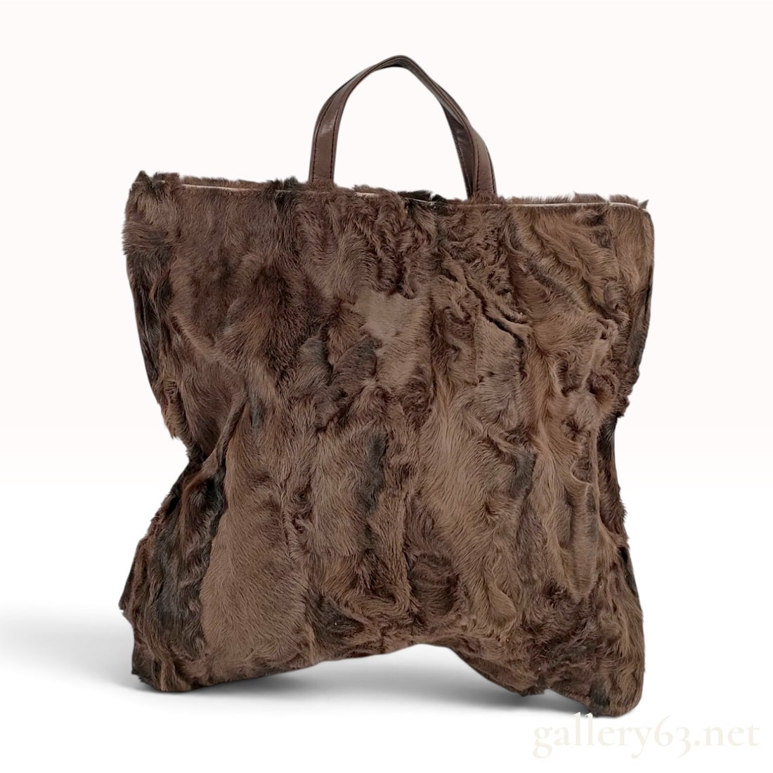 LOEWE Brown Astrakhan Fur and Leather Tote Bag: This rectangular tote bag by Loewe features a front panel made of dark brown curly Astrakhan fur and a contrasting back panel of smooth brown leather. The bag is designed with an open top and dual fla