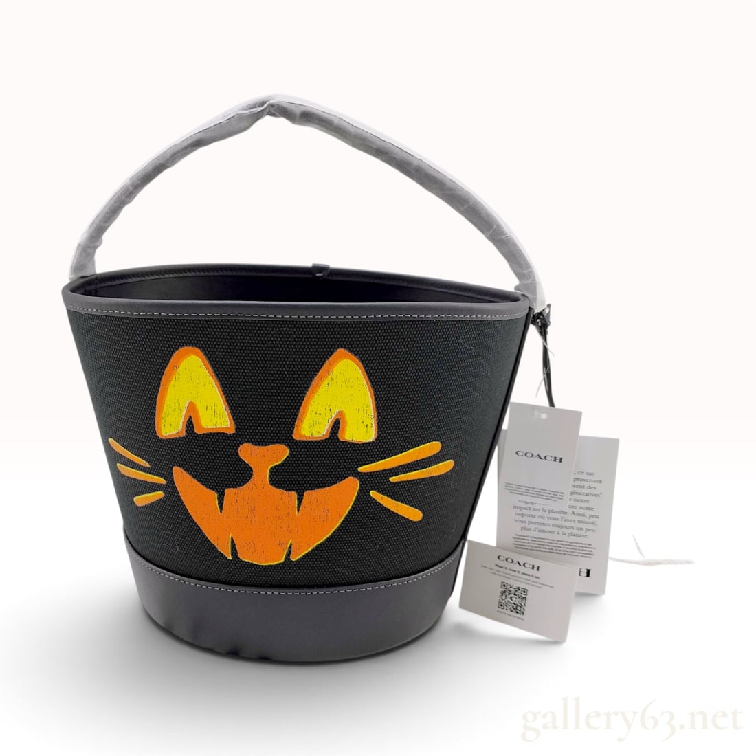 Coach Halloween Lucky Black Cat Trick-or-Treat Bucket Bag new with tags: A Coach Halloween Trick-or-Treat bucket bag featuring a stylized cat face graphic. The main body is constructed of heavy-duty black textured canvas, while the base, top rim, and handle are made of smo