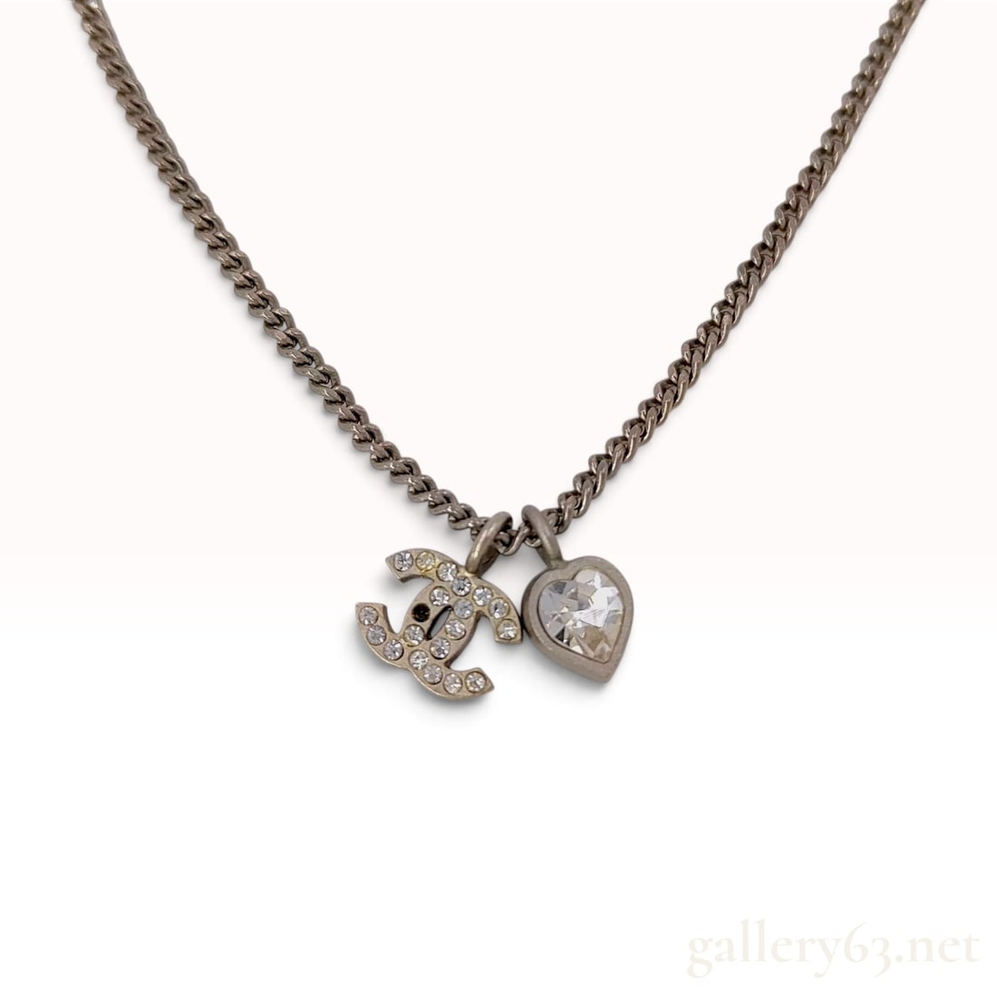 Chanel Spring 2011 Crystal CC and Heart Charm Necklace: A Chanel designer costume jewelry necklace from the Spring 2011 collection. The piece is constructed from a silver-tone metal with an antiqued finish and features a fine curb link chain. The necklace 
