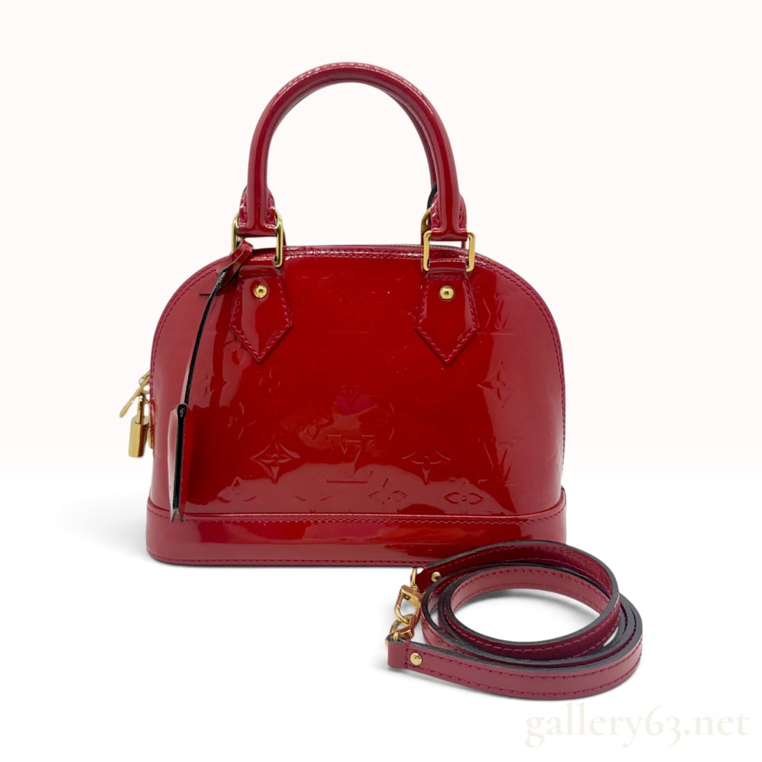 Louis Vuitton Monogram Vernis Alma BB Handbag in Pomme d'Amour: A Louis Vuitton Alma BB handbag crafted from Monogram Vernis embossed patent leather in the Pomme d'Amour red colorway. The bag is designed in a structured dome silhouette with dual rolled top handles
