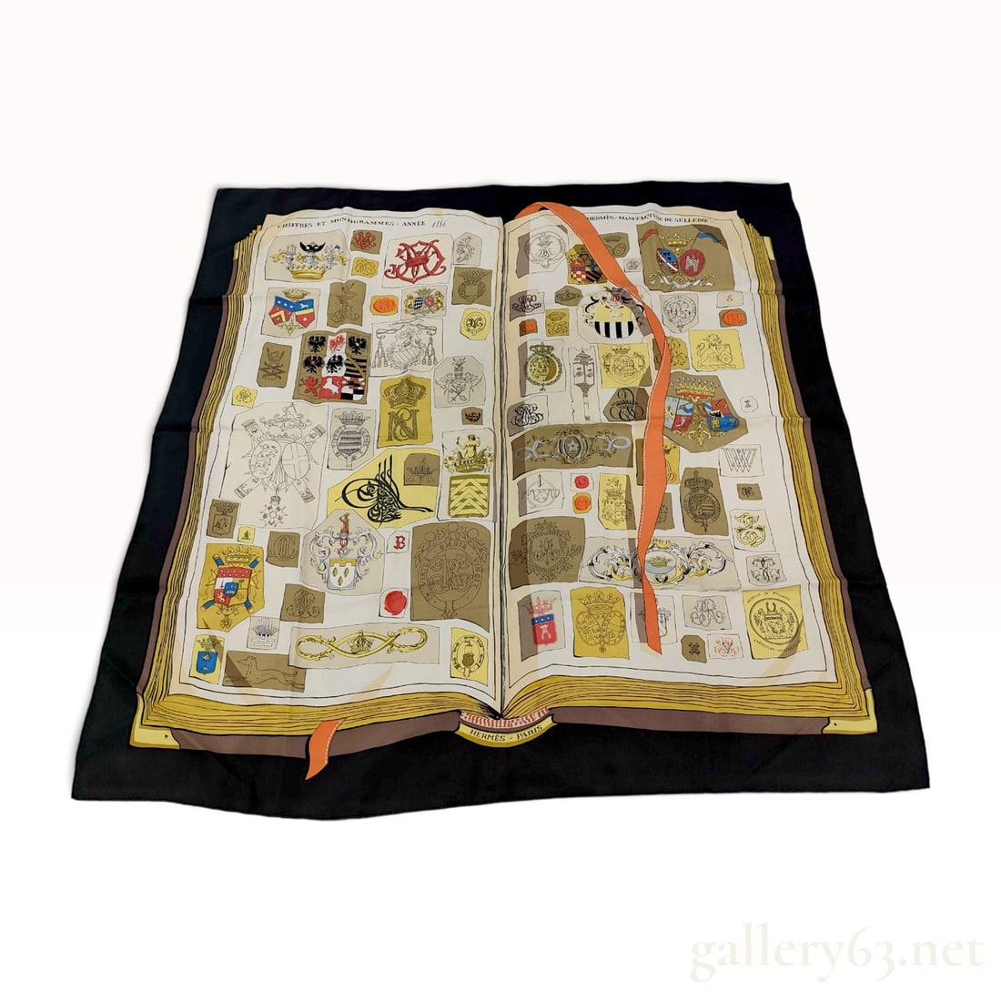 Hermes Chiffres et Monogrammes Silk Scarf: An authentic Hermes silk twill scarf featuring the Chiffres et Monogrammes pattern. The central design depicts a large open book filled with an array of heraldic crests, coats of arms, and monograms. 