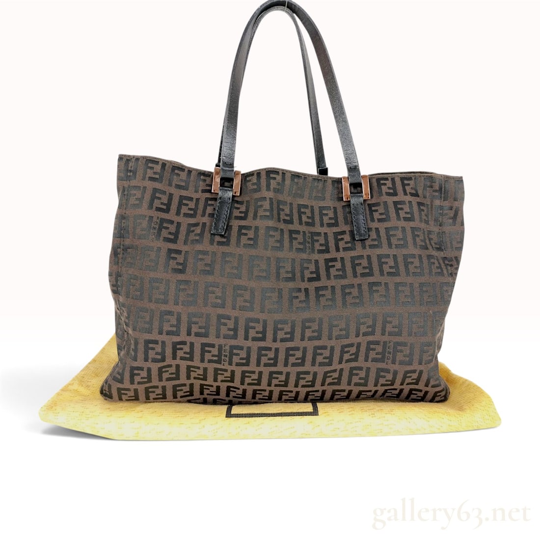 Fendi Zucca Monogram Canvas Tote Bag: Fendi Zucca monogram tote bag constructed from tobacco brown jacquard canvas with dark brown leather handles and trim. The exterior and interior lining feature the iconic FF Zucca pattern, with the FE
