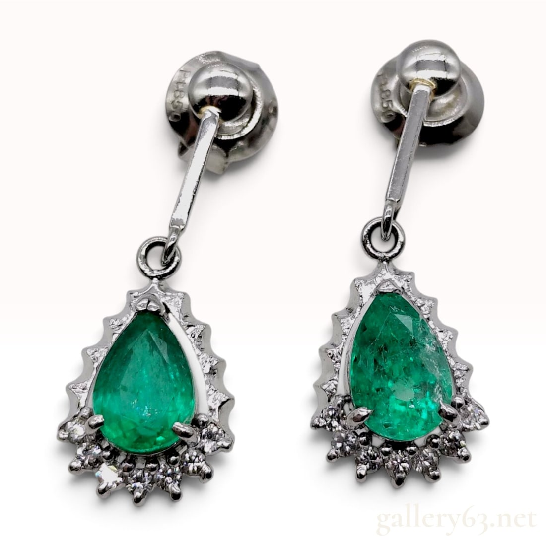 Pt850 1.38ct Natural Emerald and 0.14ctw Natural Diamond Drop Earrings: This item is in excellent condition. A pair of platinum drop earrings, each featuring a pear-cut natural emerald secured in a three-prong setting. The base of each emerald is bordered by a partial