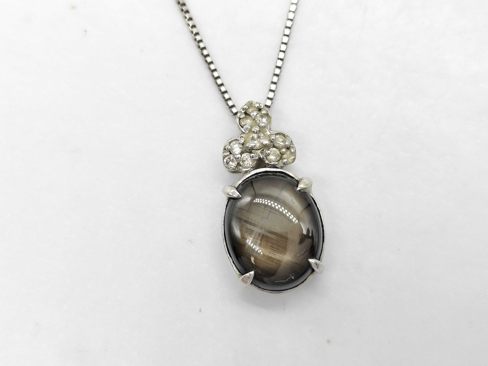 18 Karat White Gold Black Star Sapphire and Diamond Pendant Necklace: This necklace features a pendant set in 18 karat white gold with a central black star sapphire and diamond accents. The focal point is an oval cabochon black star sapphire, weighing approximately 2.91