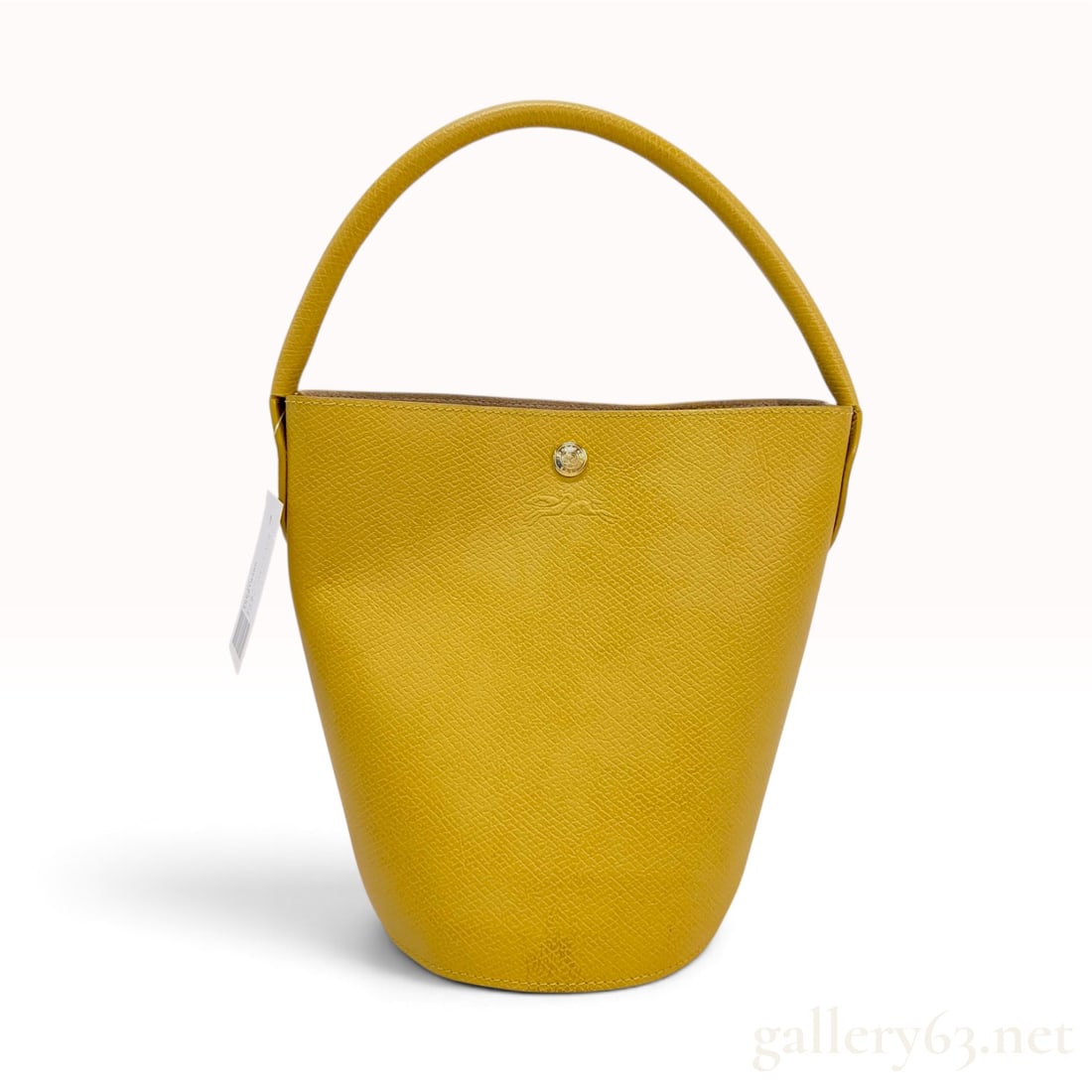 Longchamp Epure Leather Bucket Bag in Yellow: A Longchamp Epure bucket bag crafted from structured grained leather in a vibrant yellow hue. The bag features a minimalist silhouette with a single integrated top handle and a gold-tone snap button c