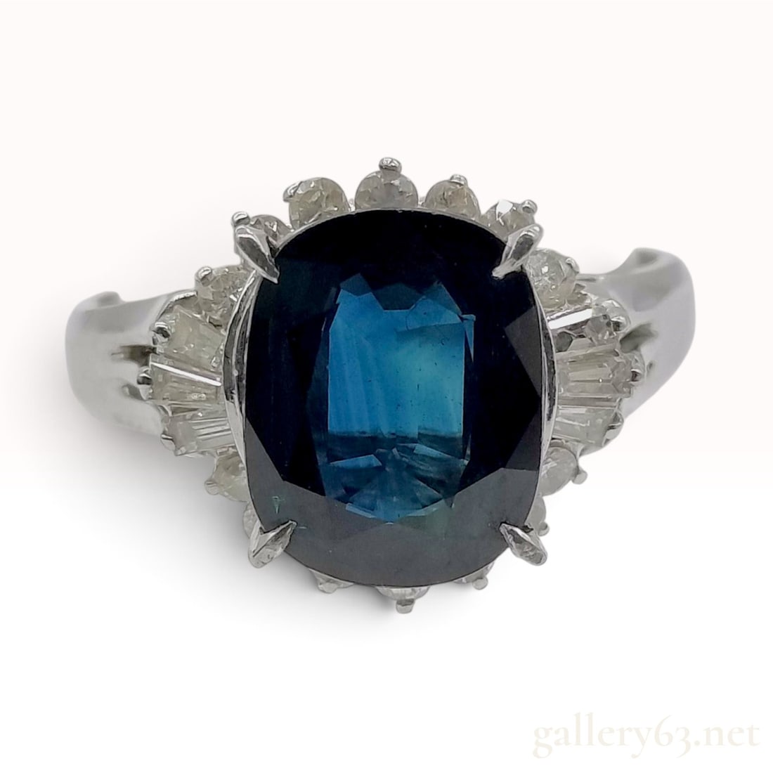 Platinum 2.92 Carat Blue Sapphire and Diamond Cluster Cocktail Ring: A platinum cocktail ring featuring a central oval-cut blue sapphire in a saturated navy hue. The sapphire is secured in a four-double-prong setting and is framed by a cluster of accent diamonds, consi