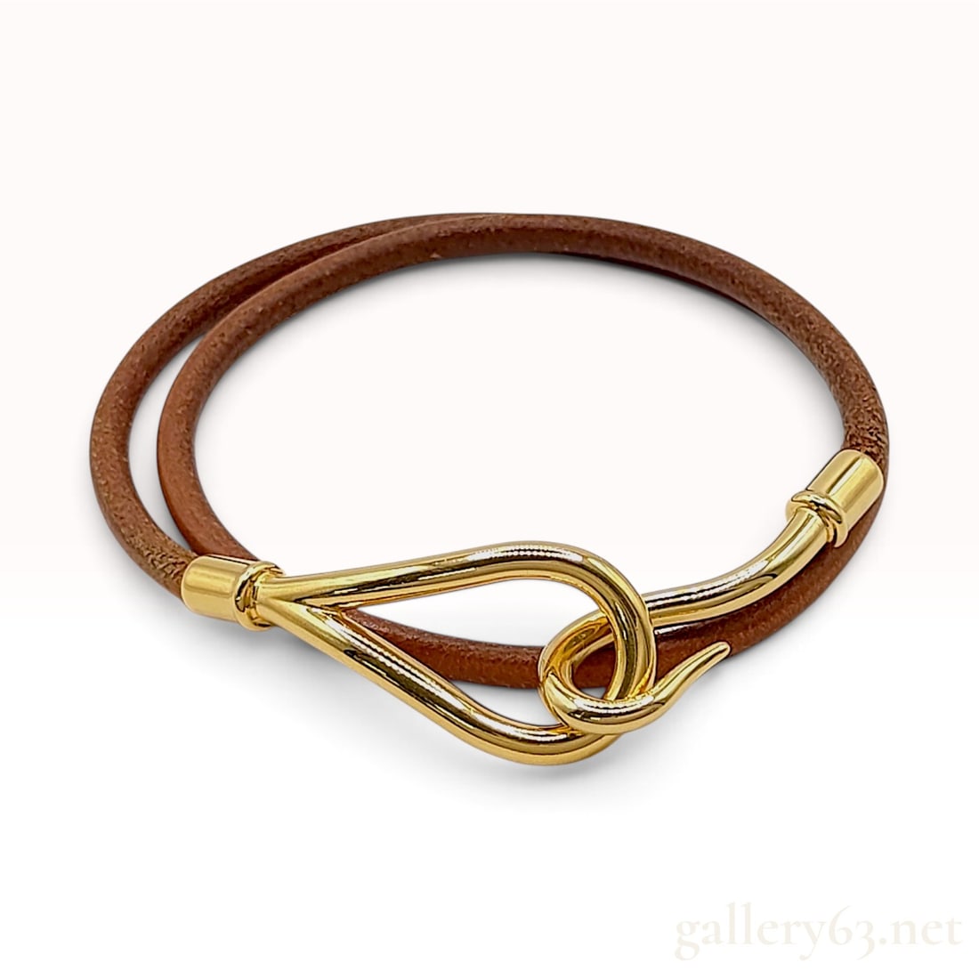 Hermes Brown Leather Jumbo Hook Double Wrap Bracelet: A Hermes Jumbo Hook double-wrap bracelet featuring a round-profile brown leather cord and gold-tone metal hardware. The bracelet is designed to wrap twice around the wrist and secures with a hook-and-