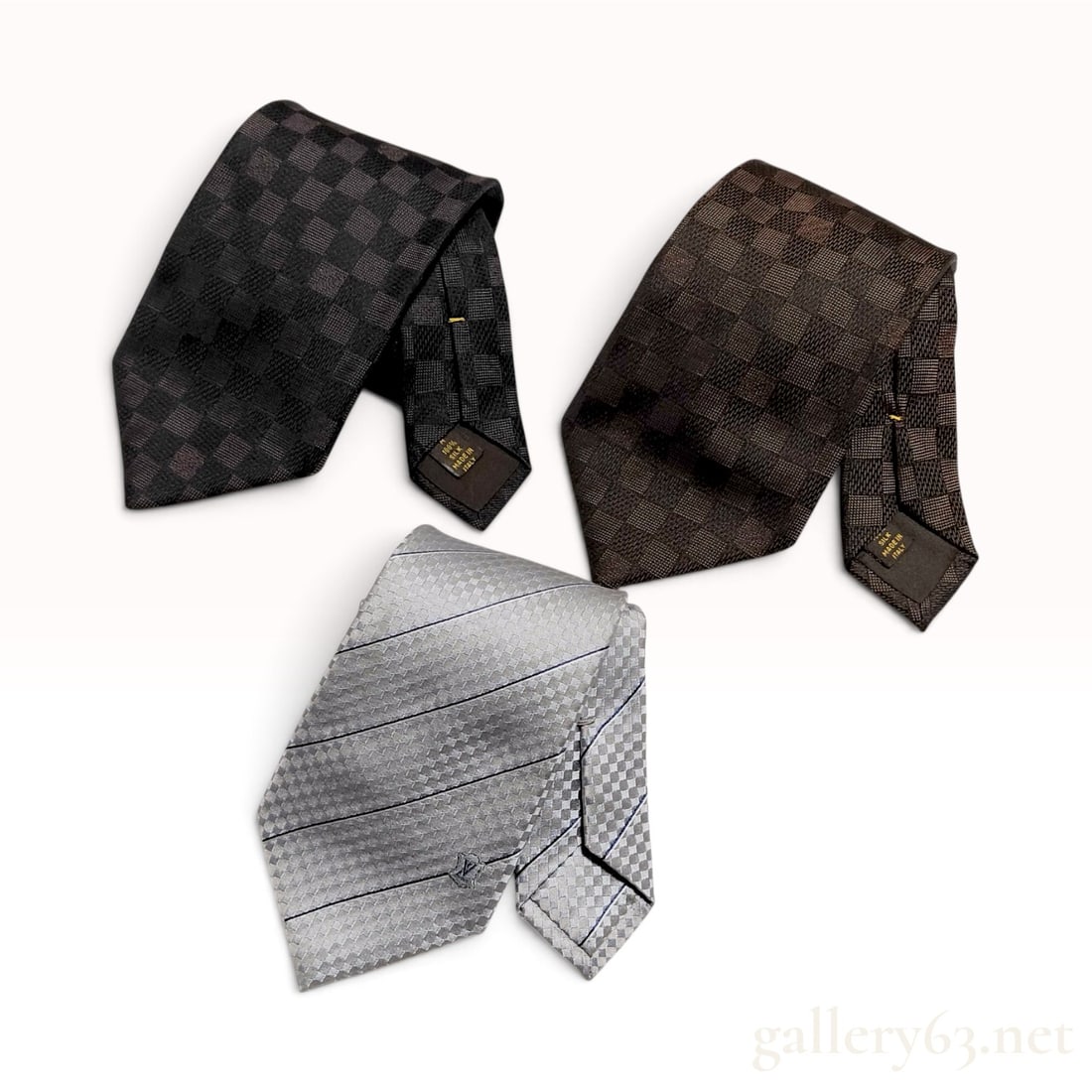 Three Louis Vuitton Damier Pattern Silk Neckties: Three Louis Vuitton men's neckties constructed of 100 percent silk. This lot includes one charcoal and black checkerboard Damier Graphite pattern tie, one brown and dark brown Damier Ebene pattern tie