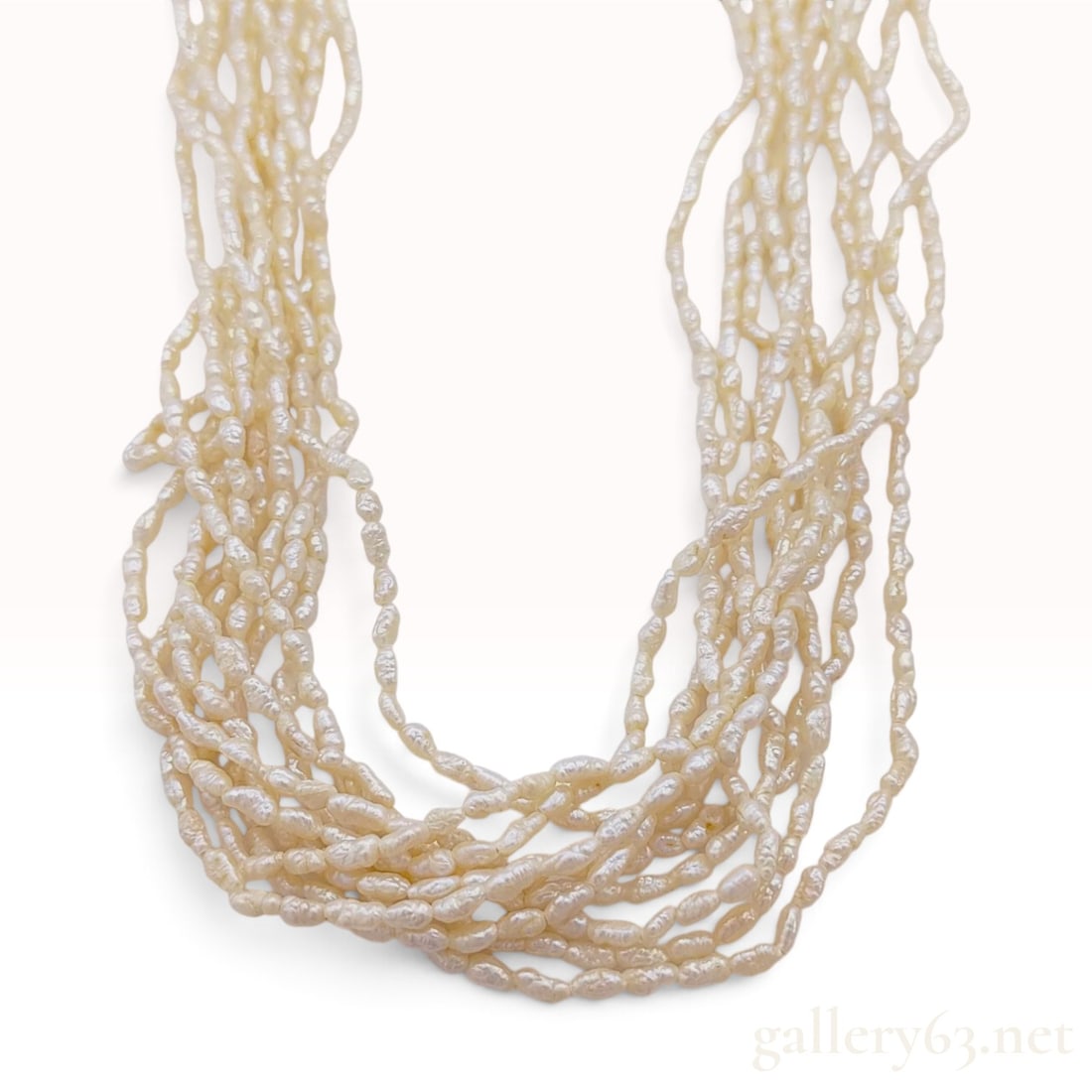 10-Strand Keshi Pearl Necklace with Silver Box Clasp: This necklace is composed of ten strands of cream-colored freshwater Keshi pearls. The pearls feature an organic, elongated form with an iridescent luster. The individual strands are secured by a deco