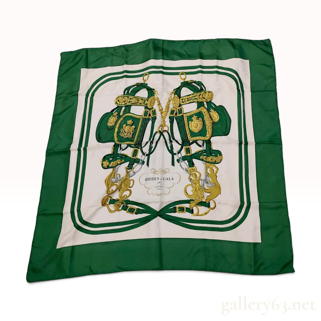 Hermes Brides de Gala Silk Carre Scarf in Green and White: An Hermes Brides de Gala silk carre scarf. The design, originally created by Hugo Grygkar in 1957, features two ornate equestrian bridles in gold and silver tones with green leather accents set agains