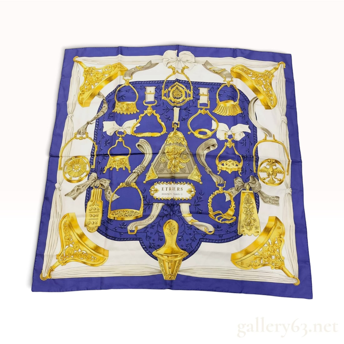 Hermes Etriers Silk Scarf by Francoise de la Perriere: Hermes silk twill scarf in the Etriers (Stirrups) pattern designed by Francoise de la Perriere. The composition features an array of historical ornate stirrups and bits in gold, silver, and grey tones