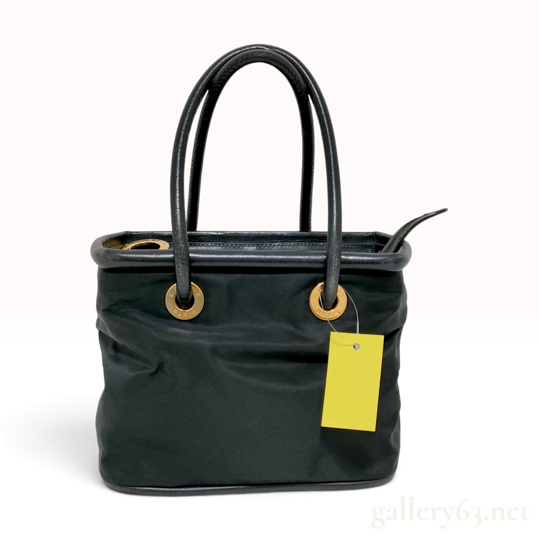 Celine Black Nylon and Leather Circle Tote Bag: A Celine small tote bag featuring a black nylon body with black leather handles, top trim, and base. The bag is designed with two rolled leather top handles secured by four gold-tone metal grommets. E