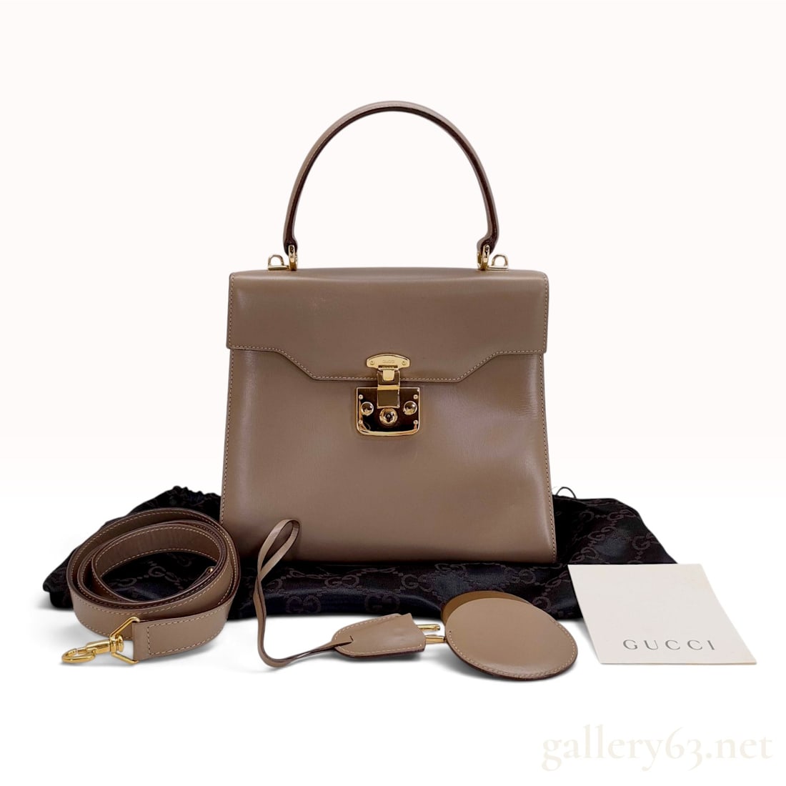 Vintage Gucci Taupe Smooth Leather Top Handle Bag with Dust Bag and Mirror: A vintage Gucci top handle bag crafted from structured smooth taupe leather. The exterior features a single leather handle and a front flap with a gold-tone push-lock closure engraved GUCCI. The base 