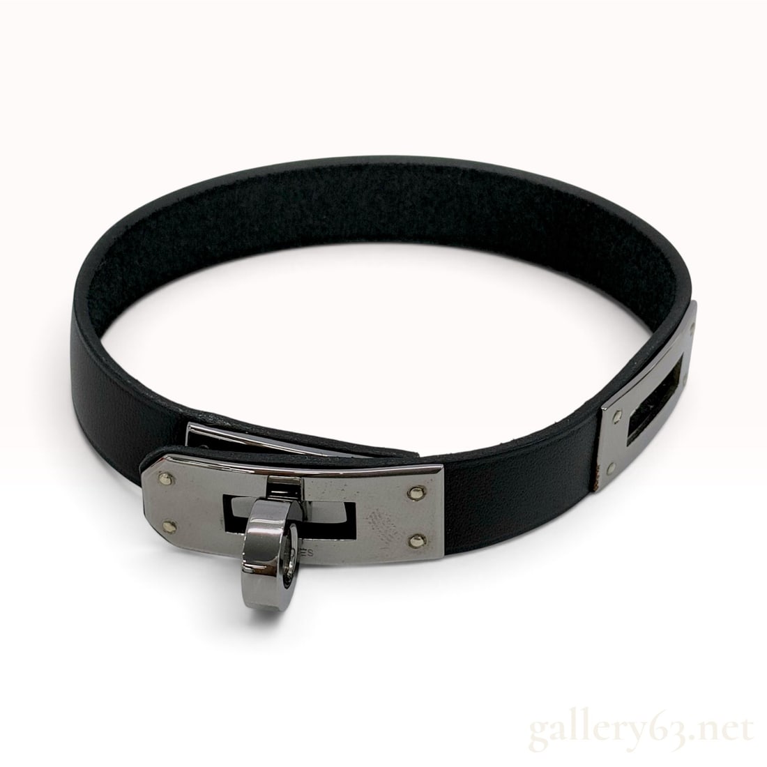Hermes Kelly Black Leather Bracelet with Box: This Hermes Kelly bracelet is crafted from smooth black leather with a dark unfinished interior and tonal edge glazing. The piece features the signature Kelly turn-lock closure mechanism in metal hard