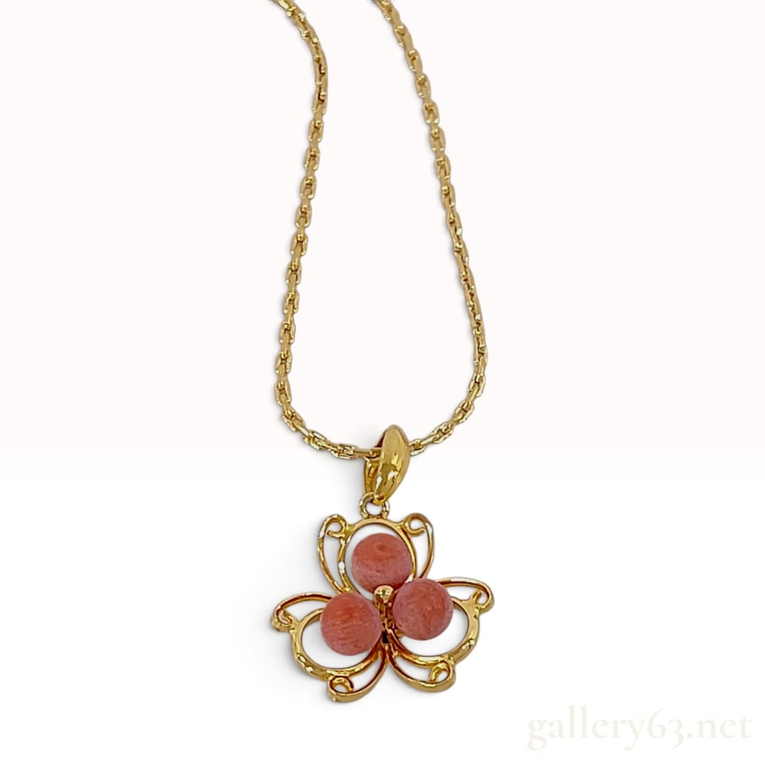 Vintage Christian Dior Pink Coral Flower Motif Gold-Tone Pendant Necklace: This vintage Christian Dior pendant necklace is crafted from gold-tone base metal and features an openwork stylized three-leaf clover or floral pendant. Three spherical pink coral-style beads with a t