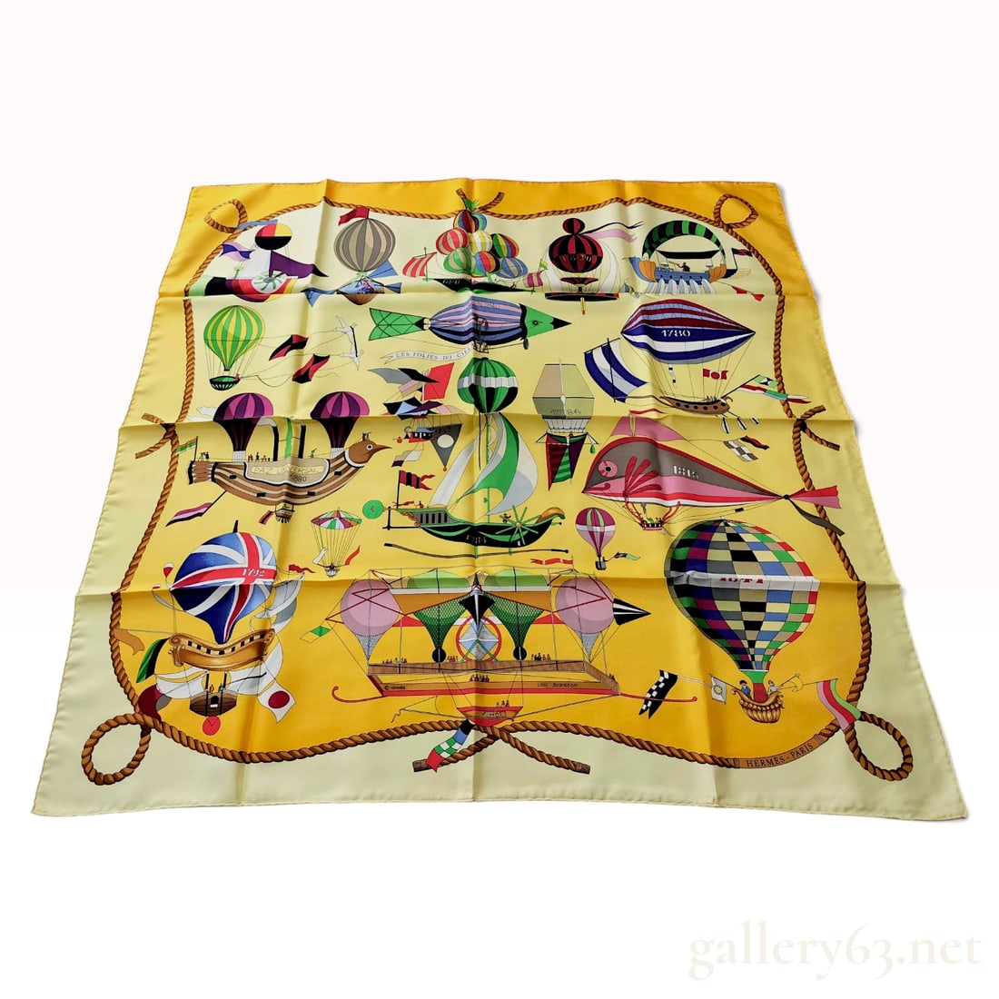 Hermes Les Folies du Ciel Yellow Silk Carre 90: This Hermes silk carre 90 is crafted from silk in the Les Folies du Ciel pattern designed by Loic Dubigeon. The whimsical illustration depicts early aviation history and fantastical flying machines, f