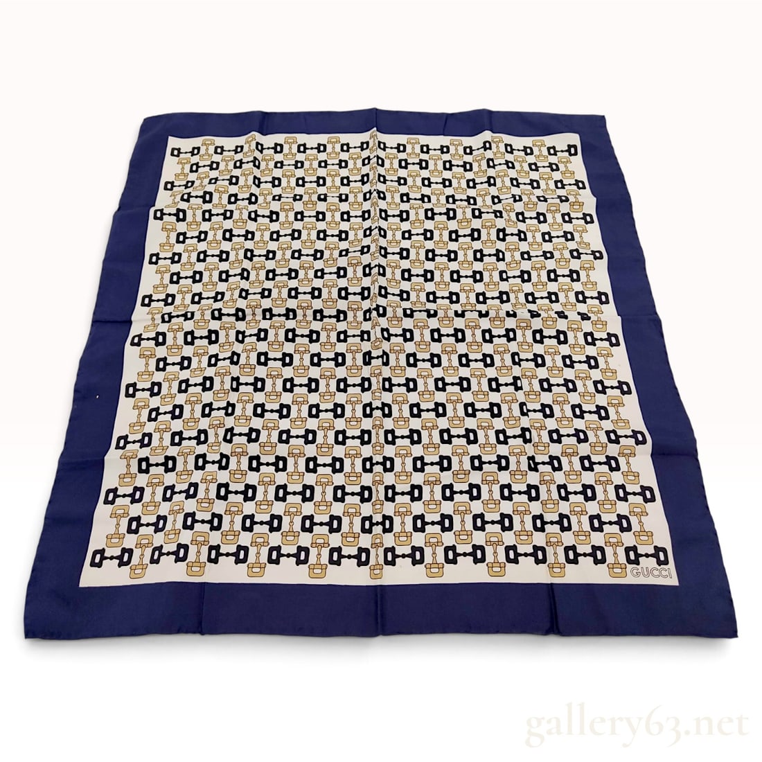 Vintage Gucci Horsebit Motif Navy and Cream Silk Scarf 67 cm: A vintage Gucci silk scarf featuring the house's signature horsebit motif. The equestrian-inspired pattern is rendered in navy blue and gold-tone across a cream-colored field, framed by a wide navy bl