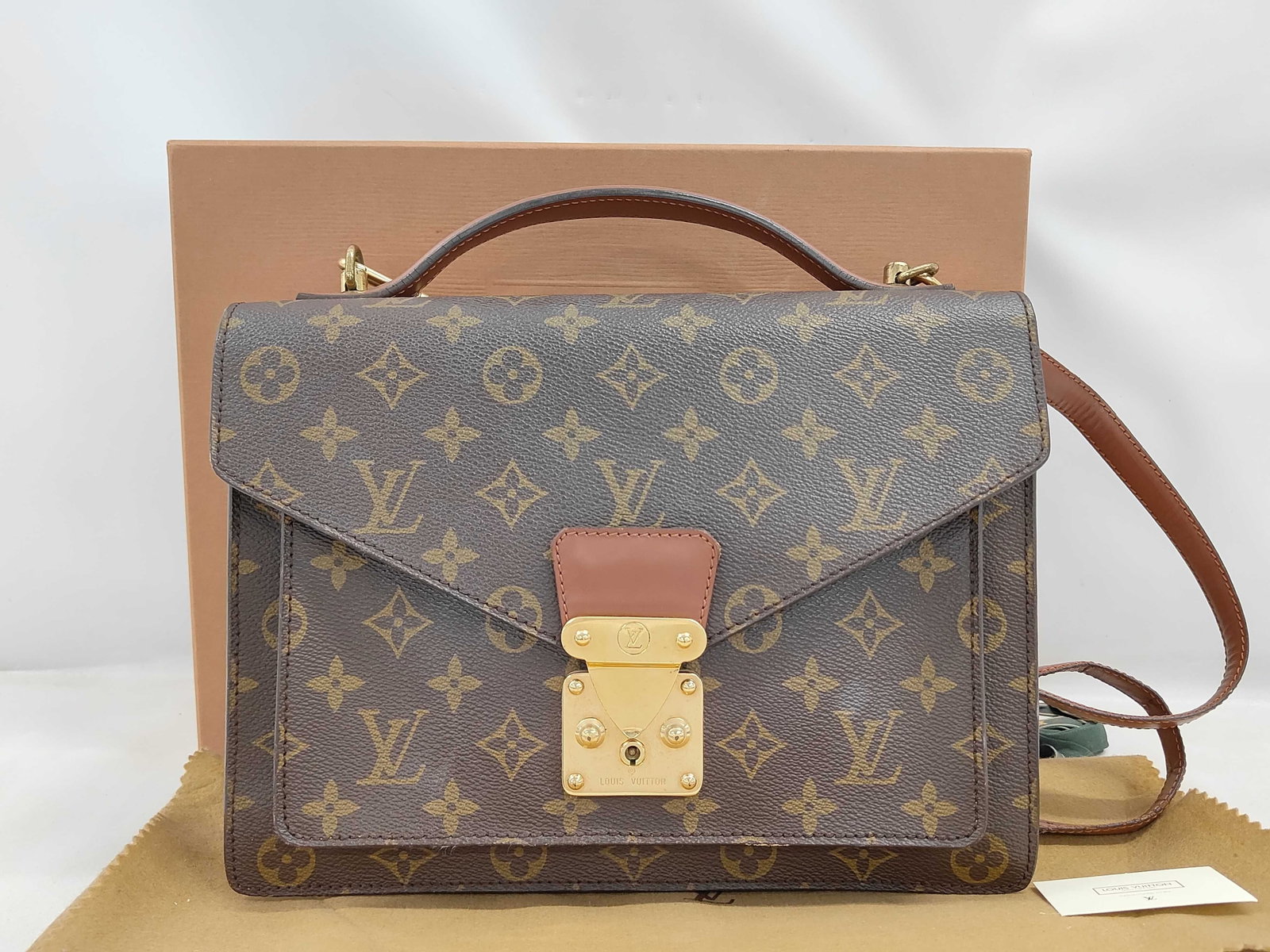 Vintage Louis Vuitton Monogram Coated Canvas Top Handle Handbag: This vintage Louis Vuitton handbag is crafted from signature Monogram coated canvas with vachetta leather trim. The satchel-style bag features a single leather top handle and a detachable, adjustable 