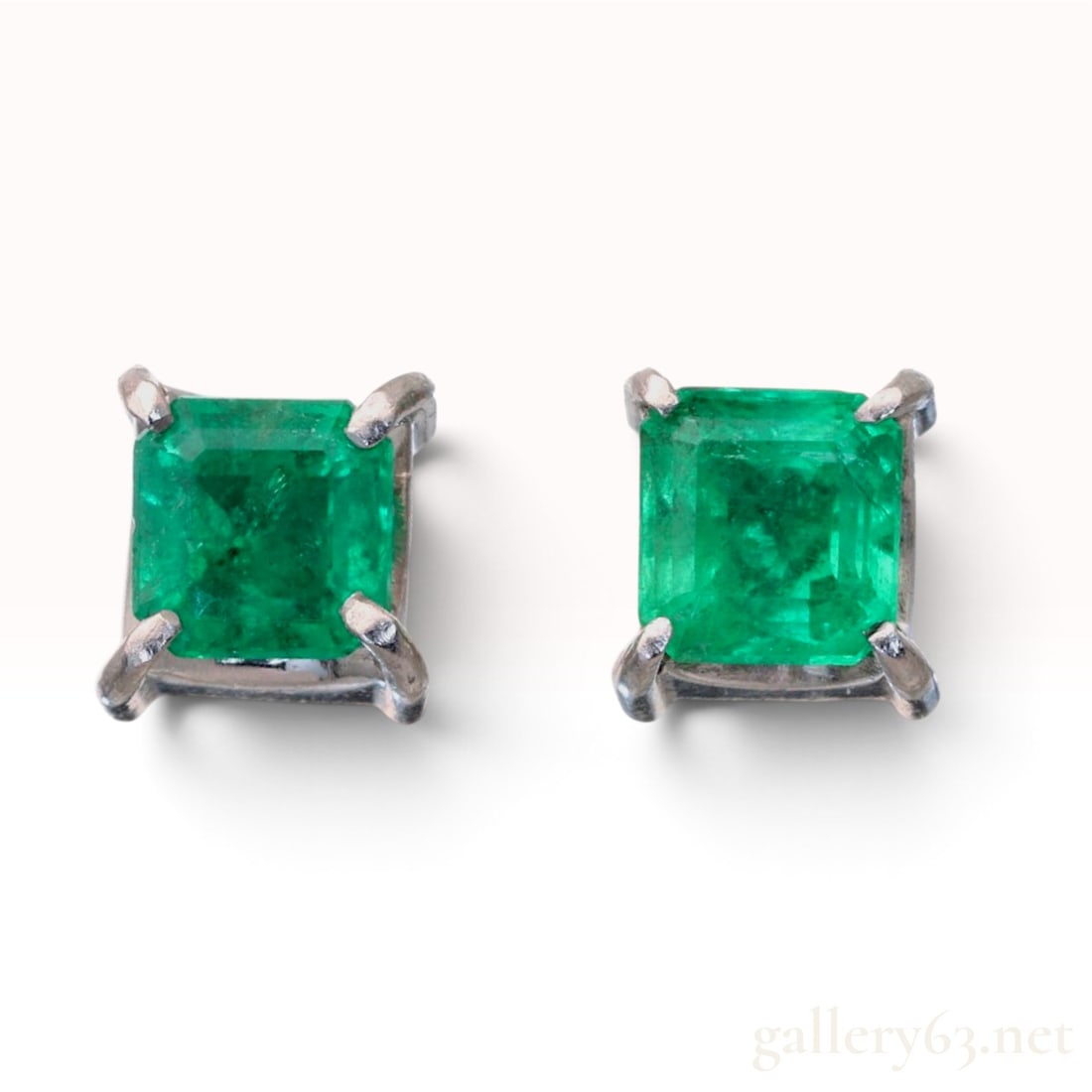 A Pair of Platinum and 0.40ctw Natural Emerald Stud Earrings: This is a pair of natural emerald stud earrings set in platinum. Each earring features a square emerald-cut green emerald held in a four-prong basket mount. The stones display a saturated green color 