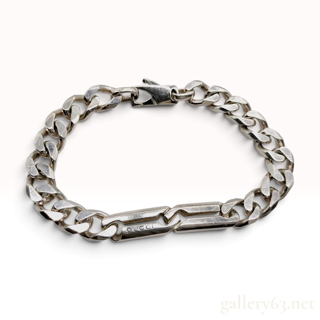 Gucci Infinity Knot Sterling Silver Curb Link Bracelet Size 18: A Gucci curb link bracelet crafted from sterling silver featuring a central infinity knot hardware element. The design consists of a polished curb link chain joined to a two-part central bar with an i