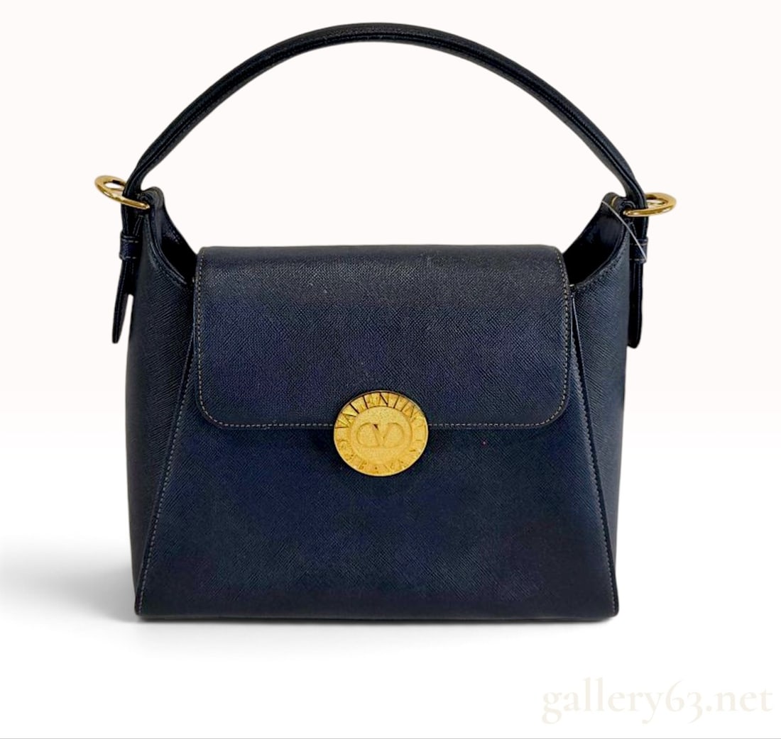 Vintage Valentino Garavani Navy Saffiano Leather Top Handle Bag with Tag: This Valentino Garavani handbag is crafted from structured navy blue Saffiano-textured leather featuring contrasting tan stitching. The bag is designed with a single top handle secured by gold-tone bu