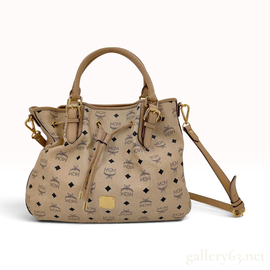 MCM Visetos Beige Coated Canvas Drawstring Bucket Bag: This MCM drawstring bucket bag is crafted from beige Visetos coated canvas featuring the signature black laurel wreath and diamond logo pattern. The bag is designed with dual rolled leather top handle