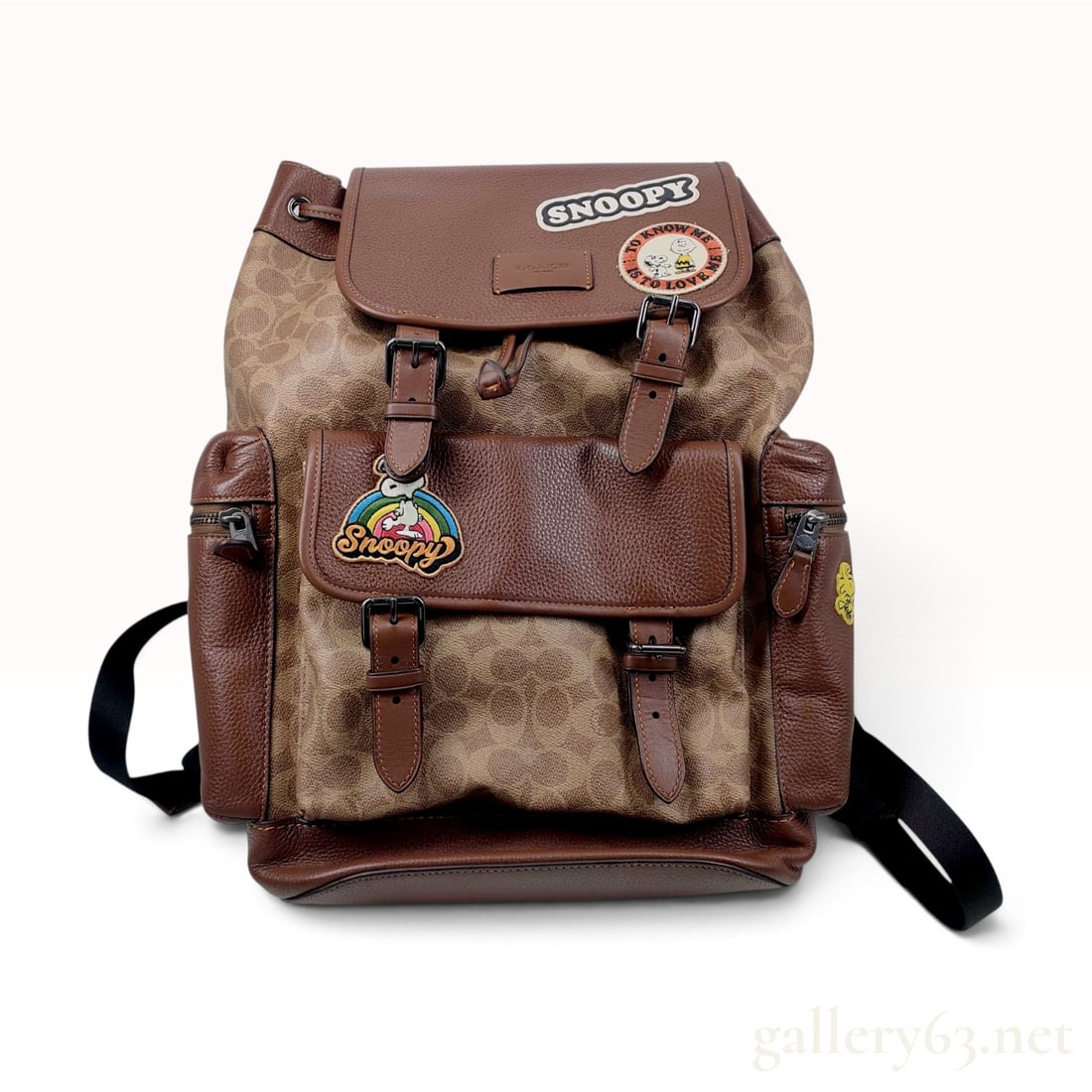 Coach X Peanuts Sprint Backpack in Signature Canvas with Patches: This Coach Peanuts Sprint backpack is crafted from signature coated canvas featuring the brand monogram pattern in khaki and tan, complemented by dark brown pebbled leather trim. The exterior is decor